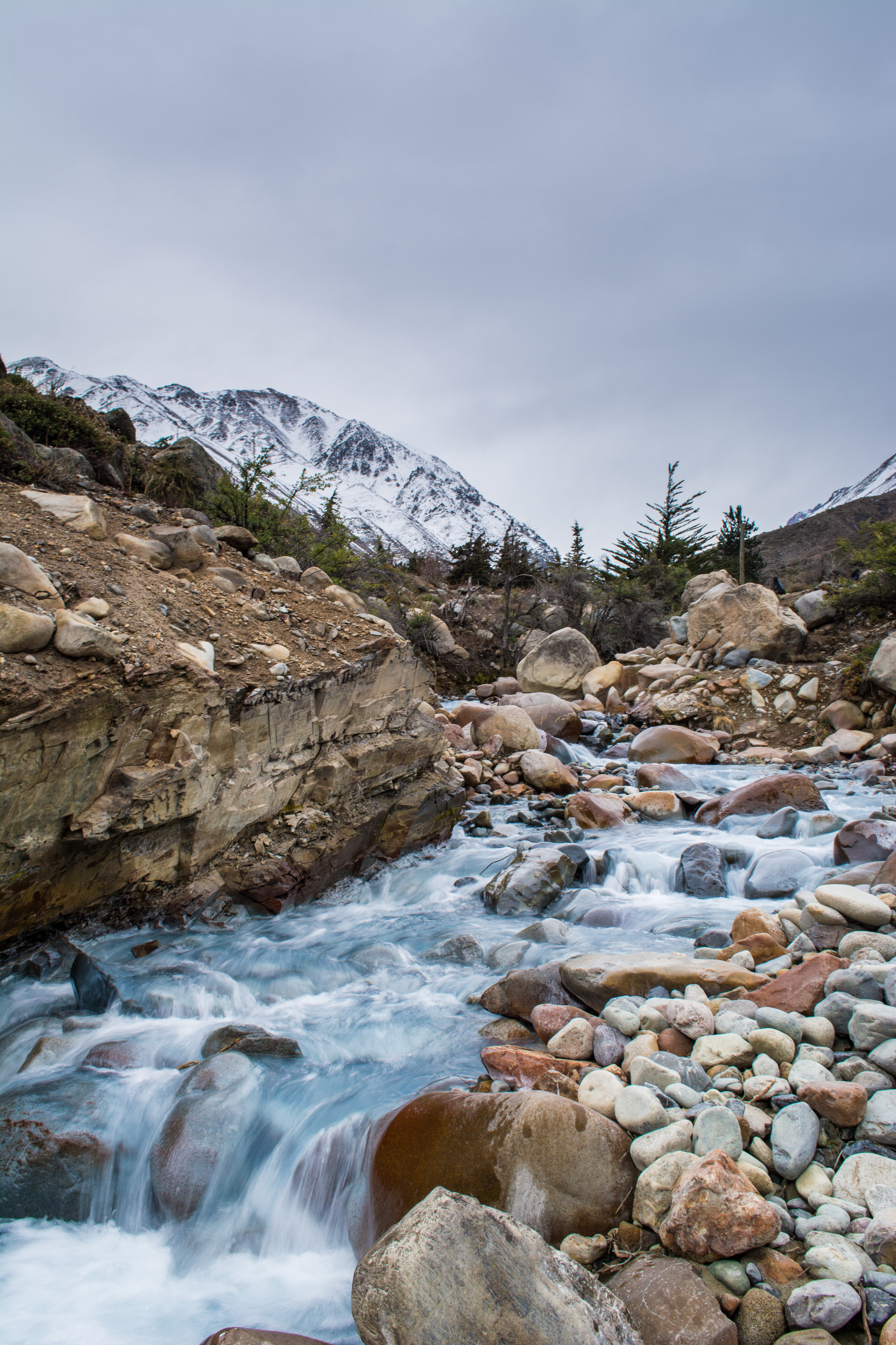 Скачать картинку Река, Скалы, Заснеженный, Поток, Камни, Горы, Природа в телефон бесплатно.